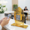 ป้ายอะคริลิคตั้งโต๊ะ QR Code สีทอง วางหน้าเคาน์เตอร์คลินิก ให้ลูกค้าสแกนติดต่อและชำระเงิน